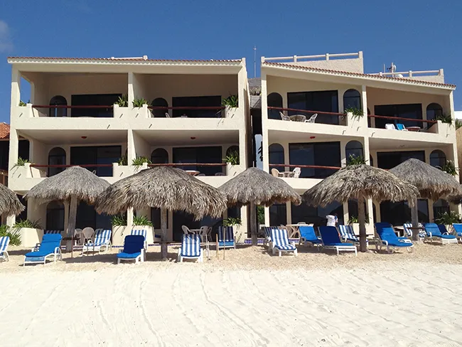 palapas and beach chairs on the beach in front of the condos